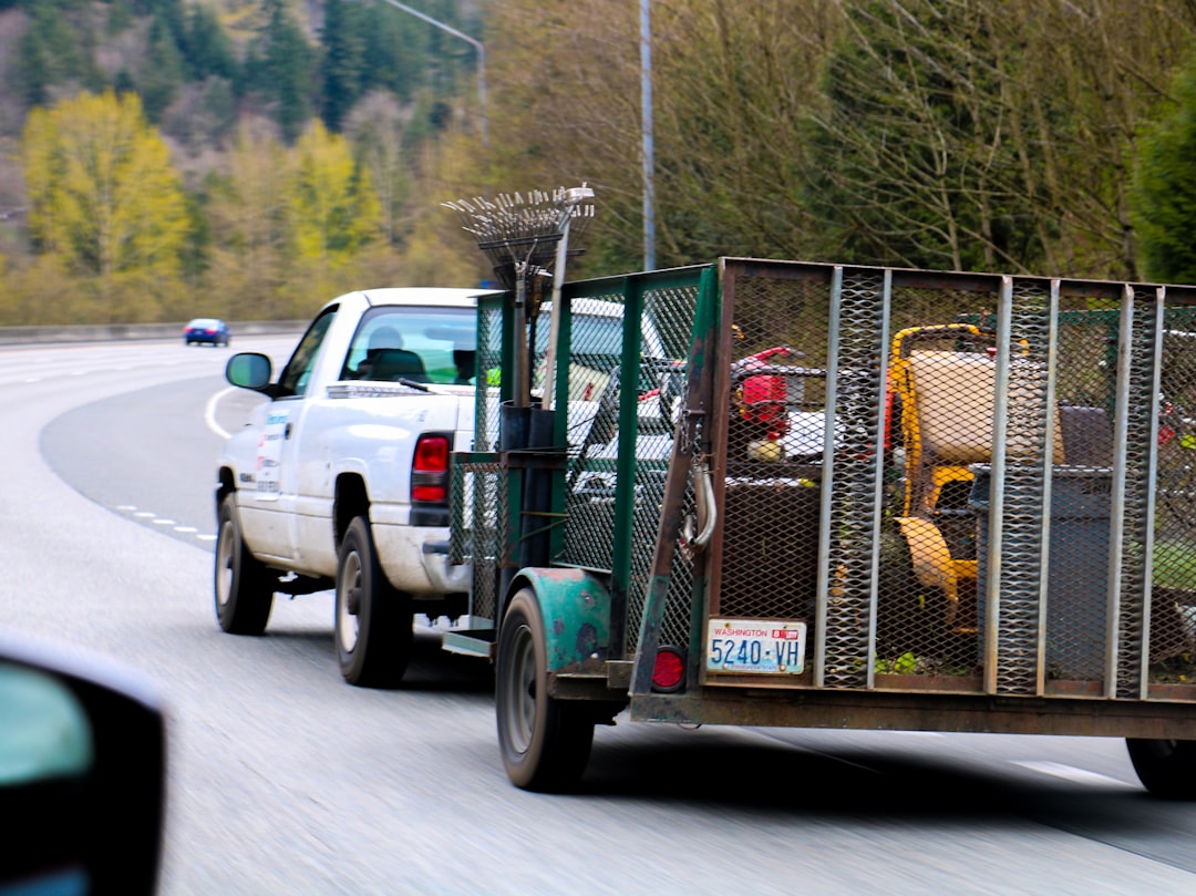 A white truck towers some lawn mowers on the highway